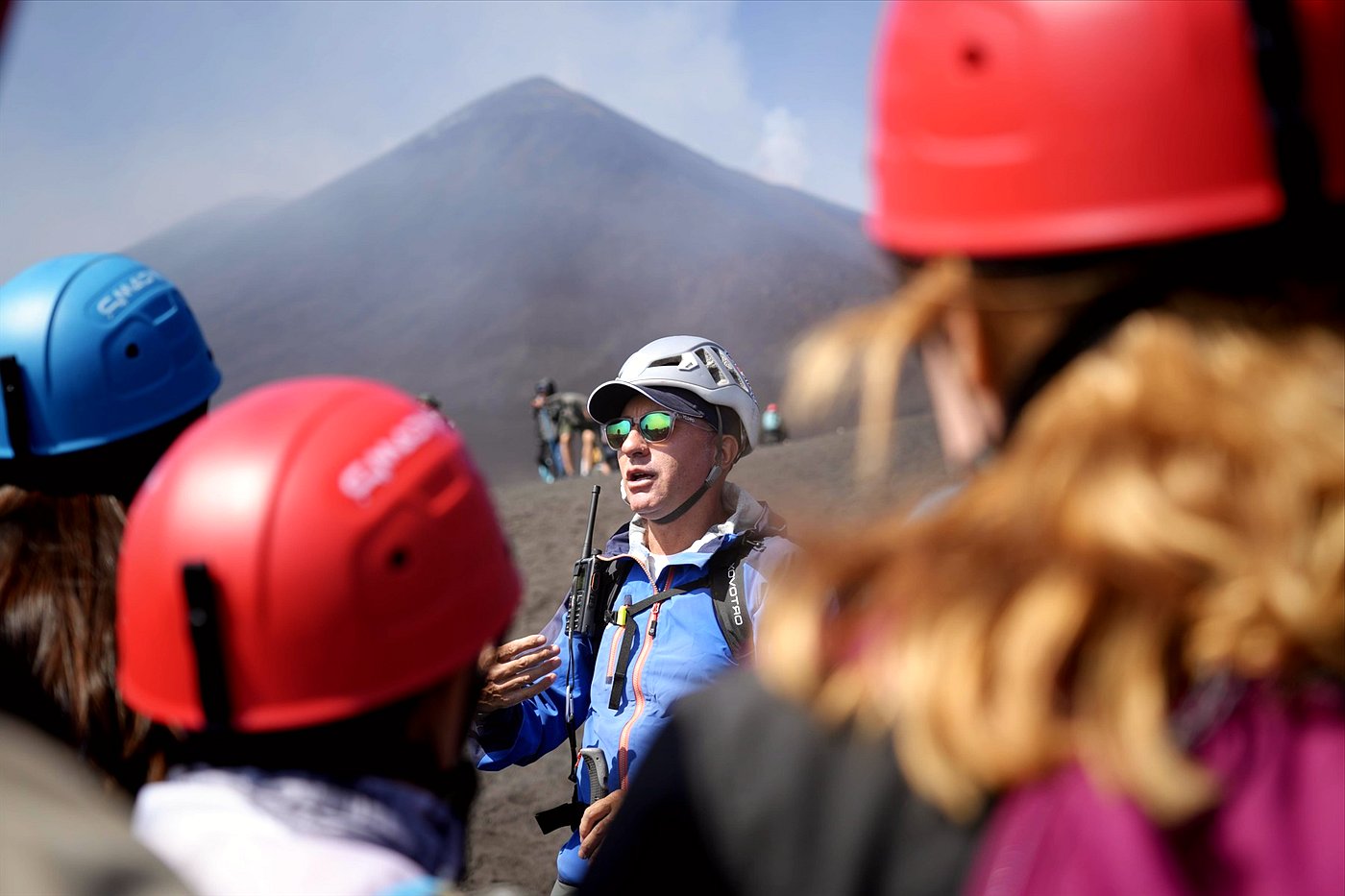 Mount Etna summit hike group with helmets walking towards the steaming craters