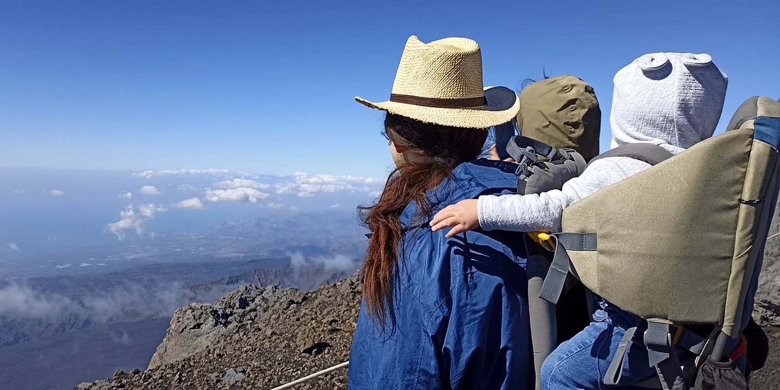Familie mit Kind in der Kraxe am Ätna über den Wolken