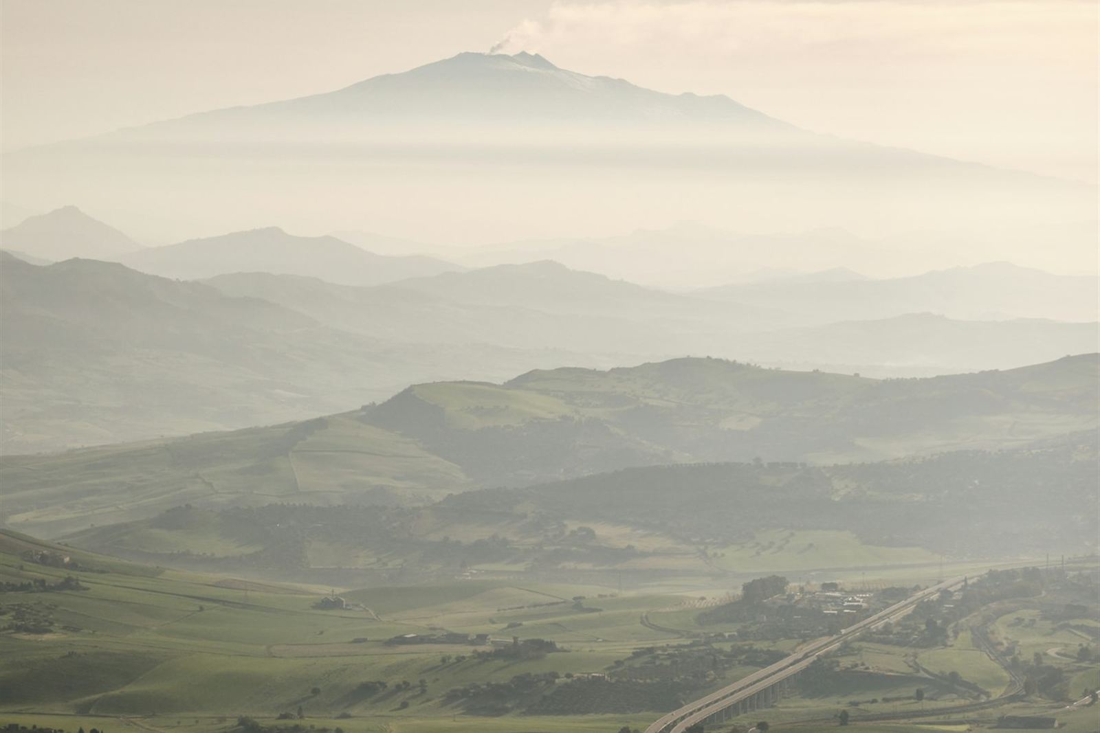 De Etna boven de heuvels van Sicilië en een snelweg in het binnenland — achtergrond rondreis Sicilië